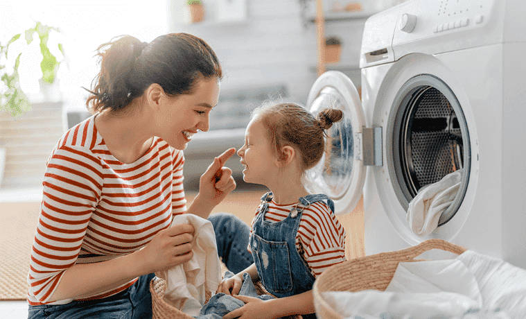 A woman does the washing with her young daughter