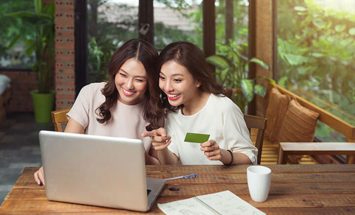 Two excited women shopping online during the Black Friday Sale