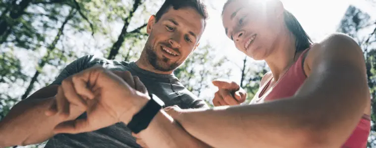 Couple outdoors looking at their smartwatches