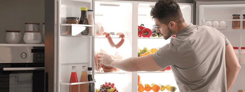 A man grabs food out of his French door fridge