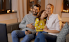 A family sitting on the couch watching TV together 