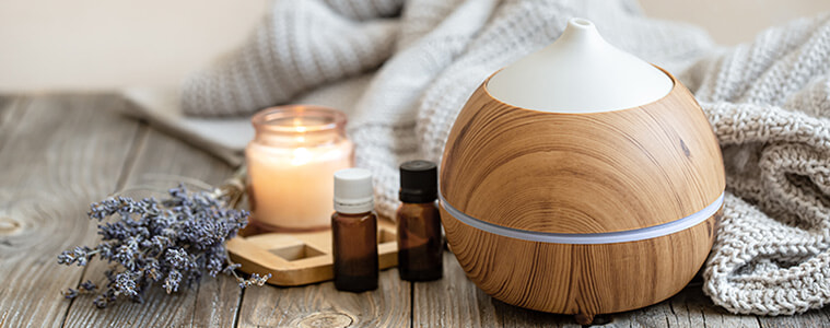 Cosy still life composition of an essential oil diffuser bottles of essential oil and a candle 