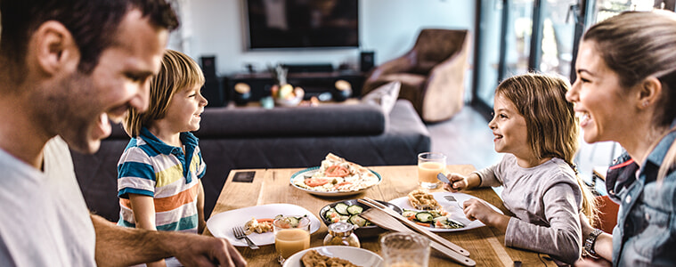 A family enjoys a meal together outside on their deck in the sunshine