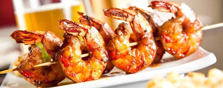 Prawn skewers on a plate served with a drink