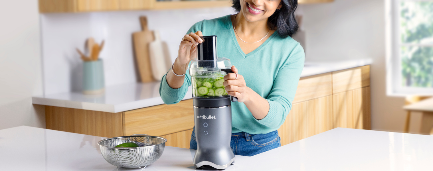 Image of a woman using the NUTRIBULLET Ultra + Total Prep System Blender to slice cucumber