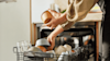 Woman stacking her Haier Dishwasher at home.