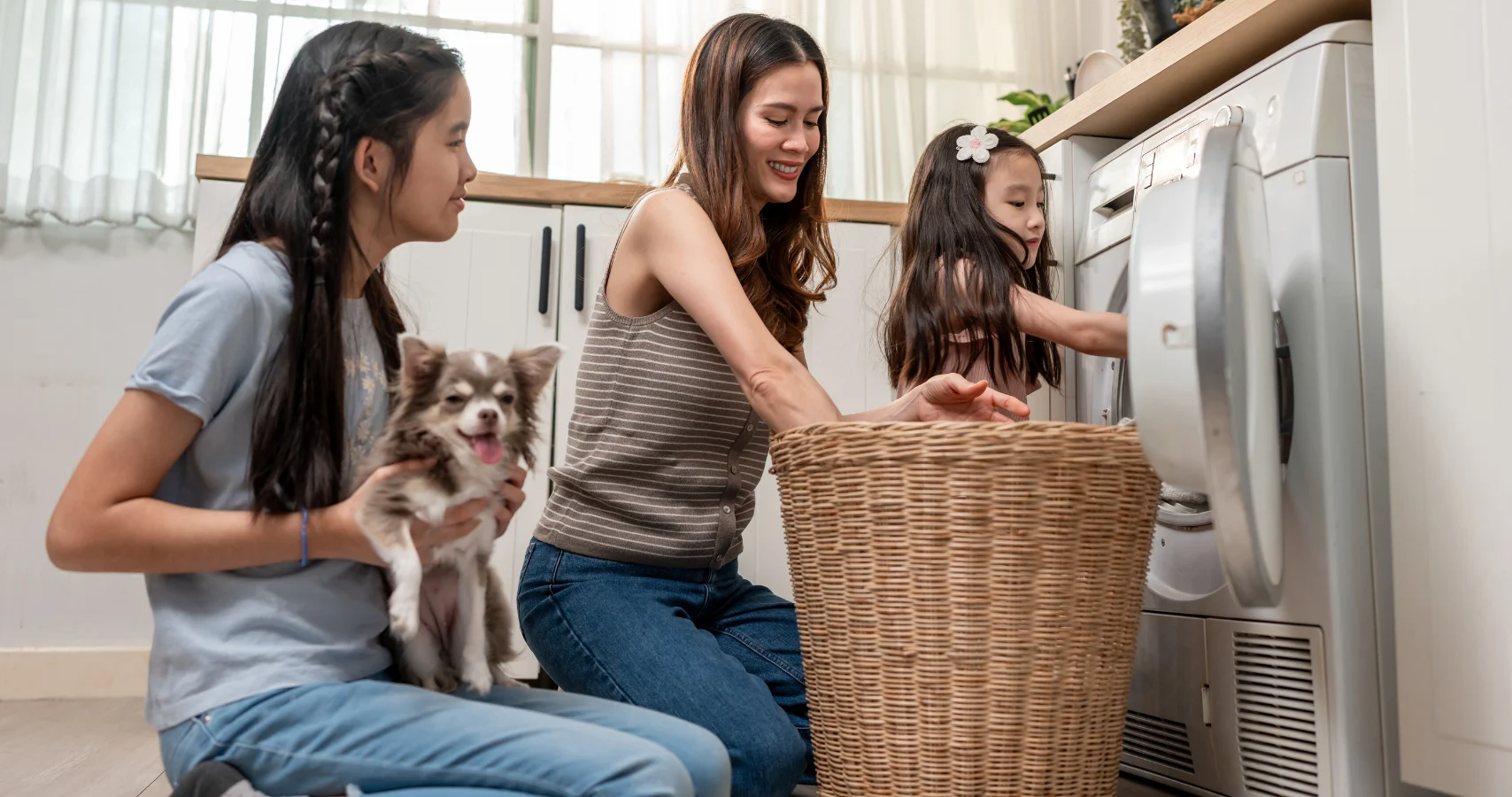 Woman and her daughters happily doing the washing with their modern clothes dryer.