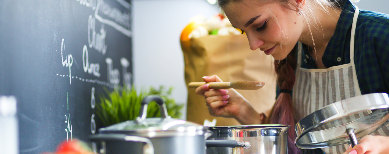 woman tasting food on cooktop