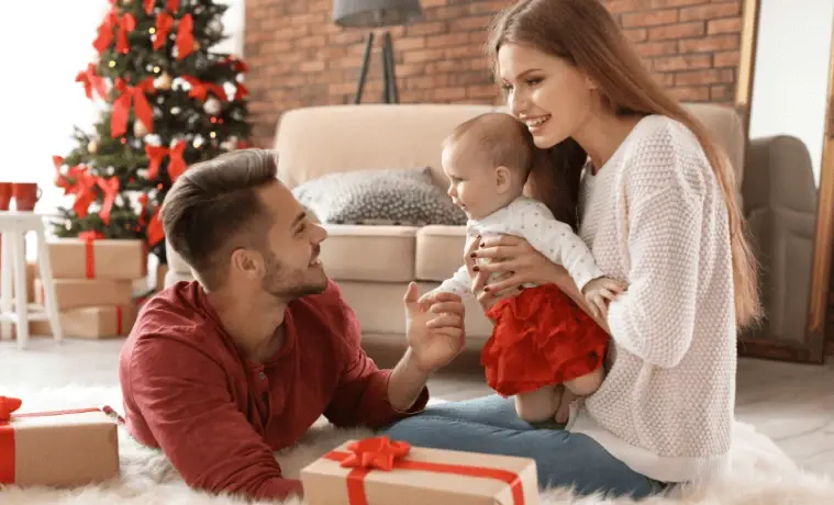 Young parents in the living room with their baby and Christmas gift