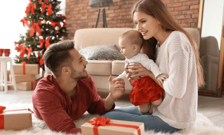 Young parents in the living room with their baby and Christmas gift
