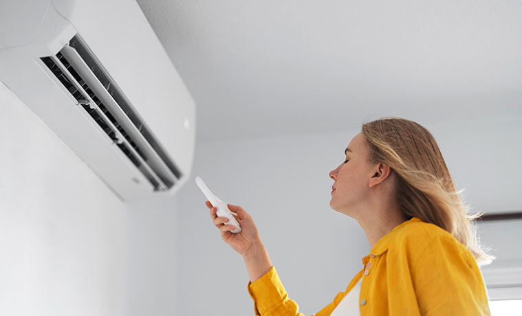 A woman enjoys a blast of cool air from her wallmounted air conditioner