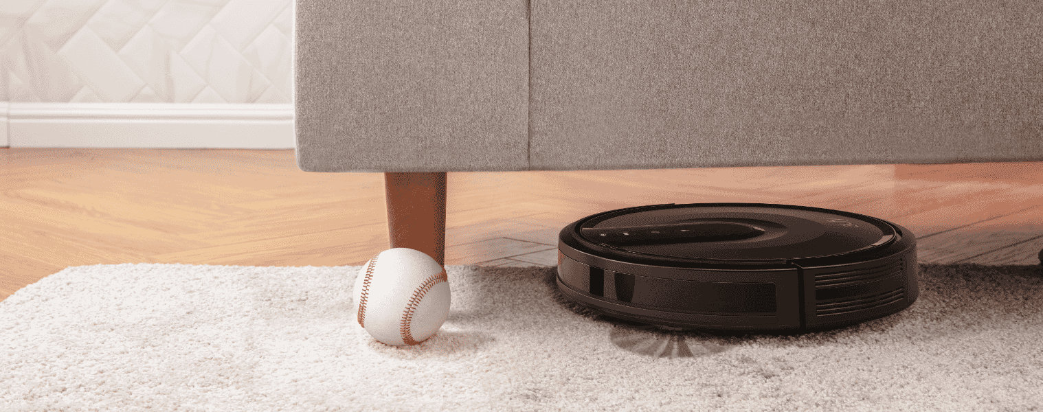 A robot vacuum cleans under a sofa
