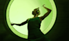 A woman dancing in front of a green background while wearing The Bose Ultra Quietcomfort Headphones