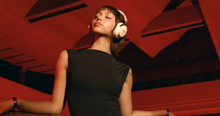 A woman dancing in front of a green background while wearing The Bose Ultra Quietcomfort Headphones