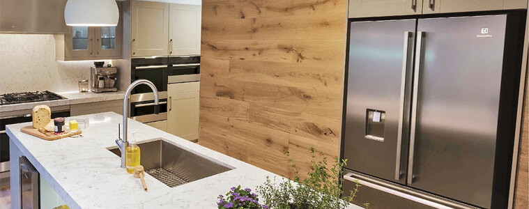 A brushed chrome gooseneck pull out mixer tap in a white and light timber kitchen