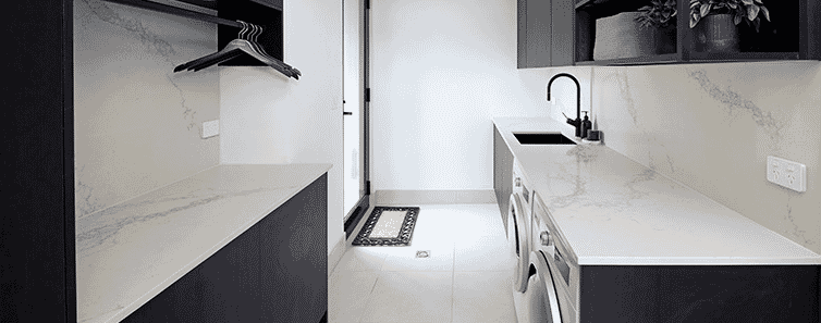 Highend laundry with dark timber cabinets marblelook benchtops builtin hanging rail above the bench and open shelving detail in overhead cupboards