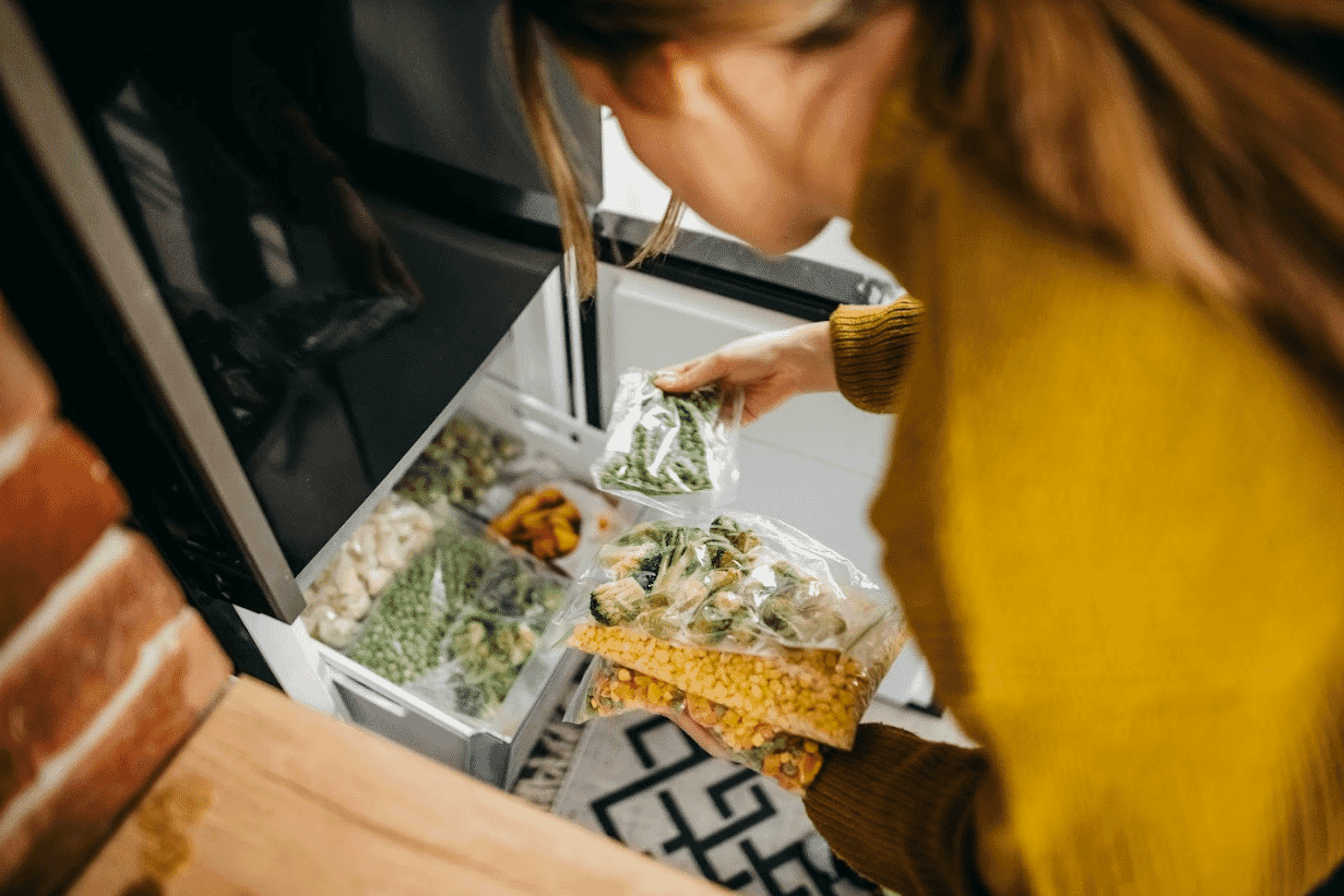 Woman putting portions of mixed vegetables into the freezer
