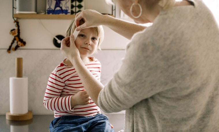 A woman applies a bandaid to a child