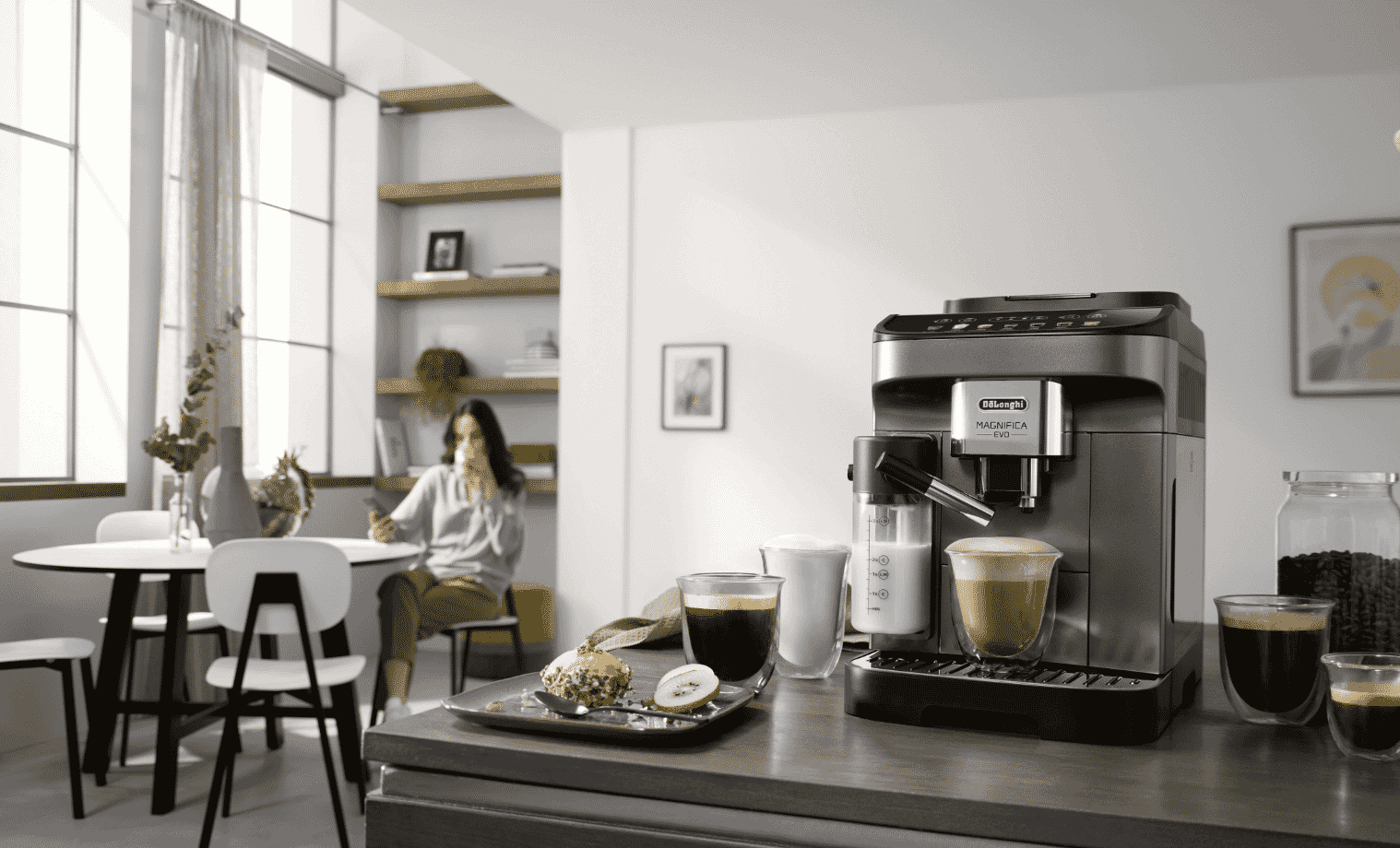 A lady in the background of the Delonghi Magnifica EVO Titan Coffee Machine
