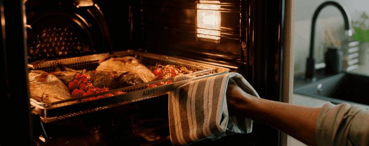 Hand places a roast to bake in a Electrolux Oven