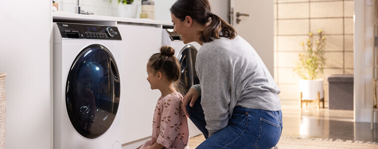 Mother and daughter watching their laundry appliance