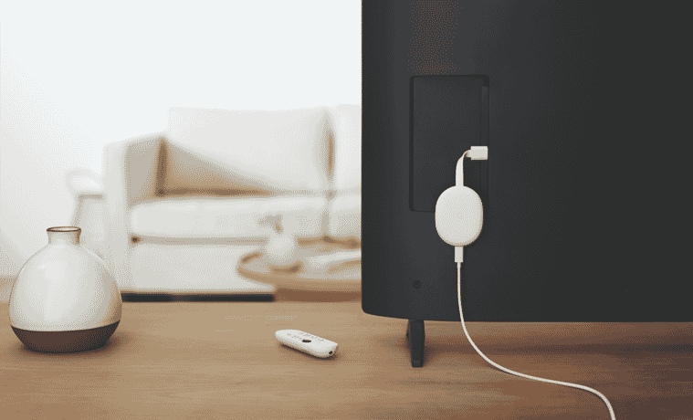 A white streaming device is attached to the back of a TV