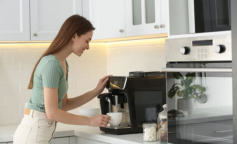 Young woman prepares fresh aromatic coffee with modern coffee machine in kitchen