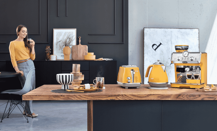 a woman standing next to her yellow DeLonghi kettle toaster and coffee machine 