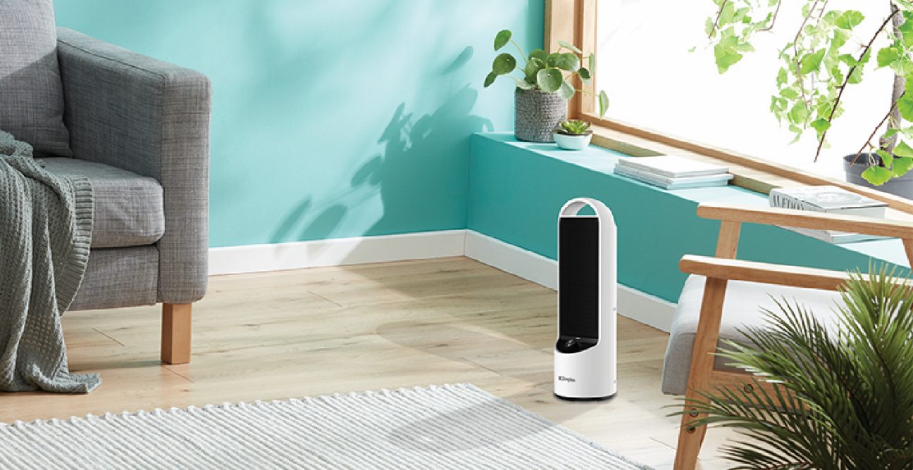 Slimline tower heater oscillating in a teal living room beside a grey armchair