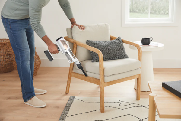 Man using Shark Handheld Vacuum to clean a sofa. 