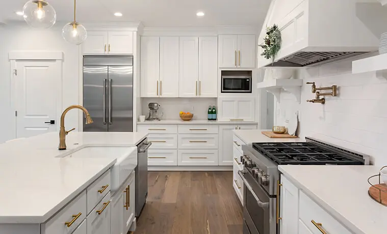 Cosy Hamptonsstyle kitchen with stainless steel side by side fridge granite benchtops and white cabinetry