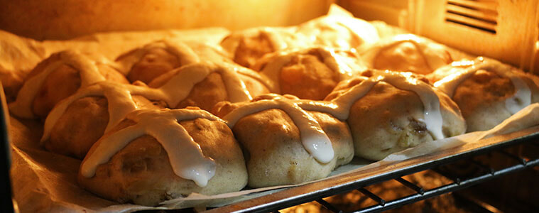 Hot cross buns cooking on a tray in the oven