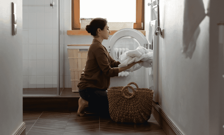 A lady pulling clothes out of her heat pump dryer in her laundry