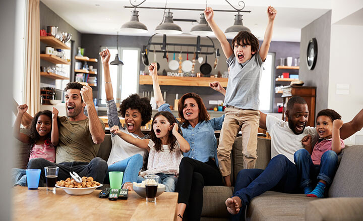 Excited group of friends watches the big game from the couch on the their new TV