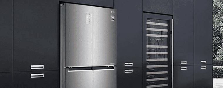 A chrome fridge sits with sleek black industrial cabinets
