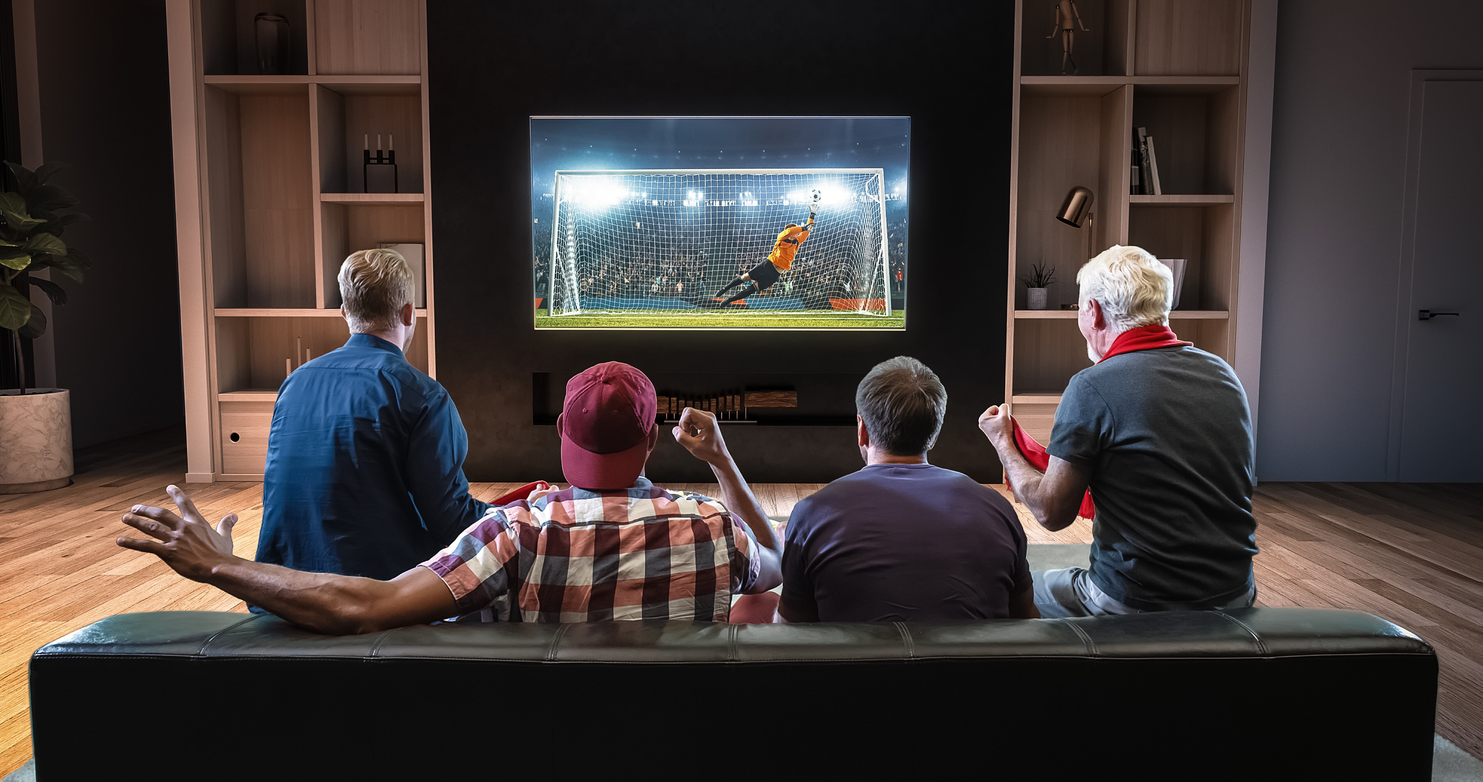 Group of fans watching a soccer moment on the TV and celebrating a goal sitting on the couch in the living room