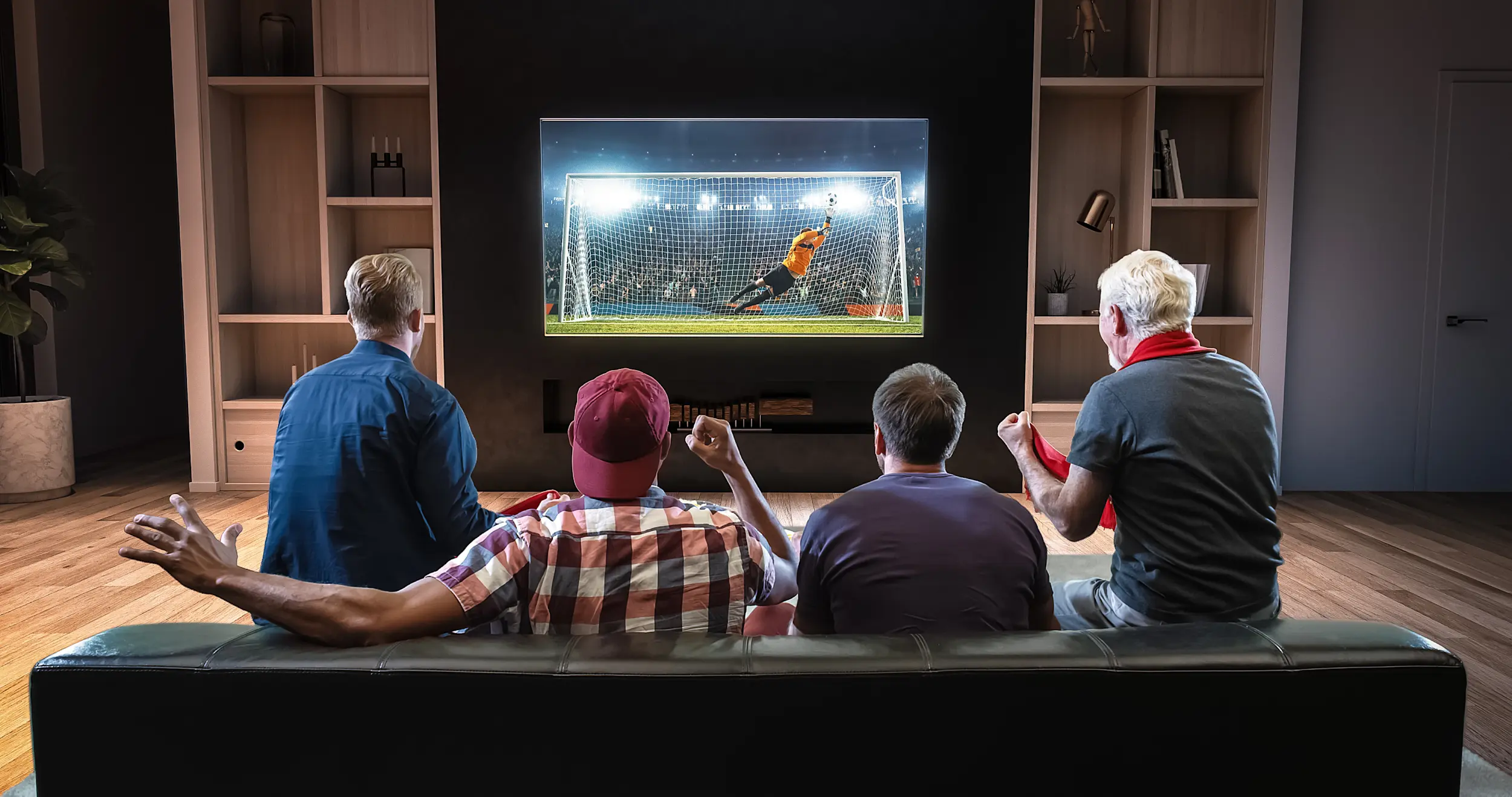 Group of fans watching a soccer moment on the TV and celebrating a goal sitting on the couch in the living room