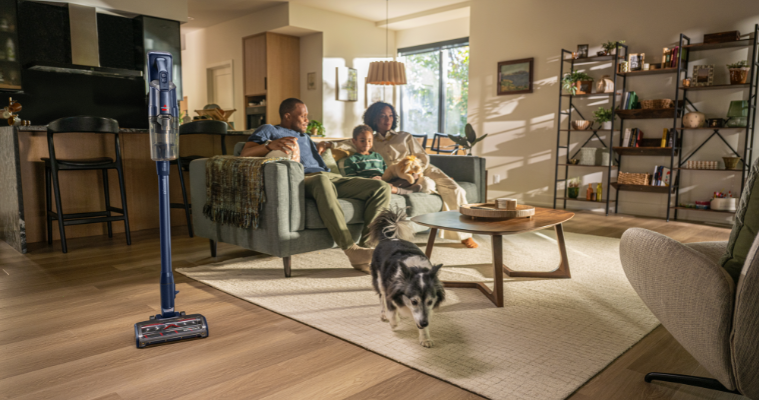Family sitting on couch with their Bissell Vacuum Cleaner close by 