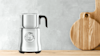 A breville milk frother on a wooden benchtop