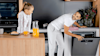 Father and daughter having breakfast together in the kitchen whilst the dad unstacks the dishwasher.
