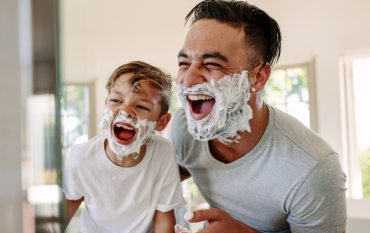 Father and son laughing with shaving foam on their faces