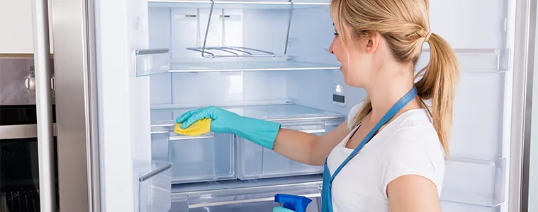 Woman cleaning the interior shelves of her fridge.