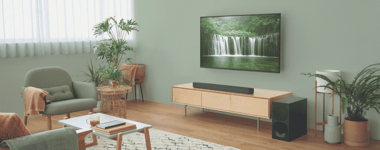 A soundbar sits on a television console and projects audio around the living room