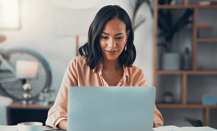 A woman checks emails on her laptop while working in her home office
