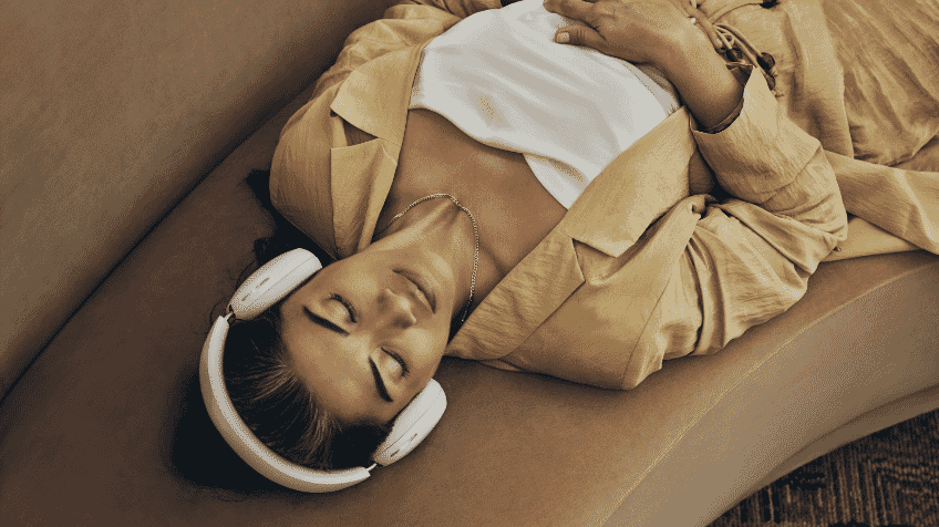 Image of woman laying on couch with Sonos Ace White headphones on