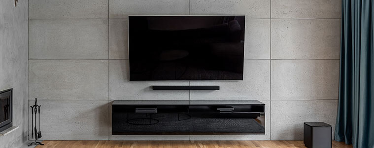 A wallmounted TV and soundbar in a contemporary grey cement living room 