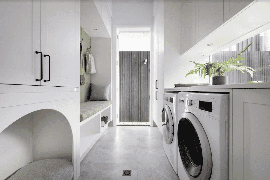 Contemporary laundry with white cabinetry builtin pet bed builtin upholstered bench seat to sit and put on shoes and side by side washing machine and dryer 