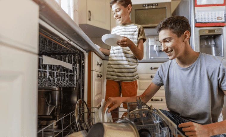 two boys packing the dishwasher together 