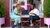 Two woman looking at laptop on table outside.