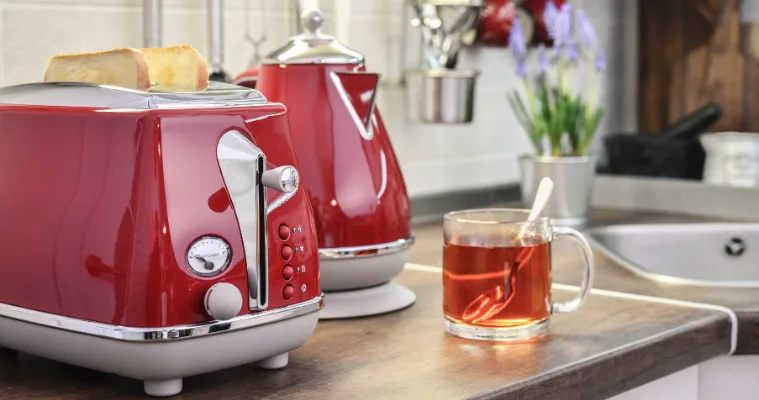A red kettle and toaster sitting on a kitchen bench